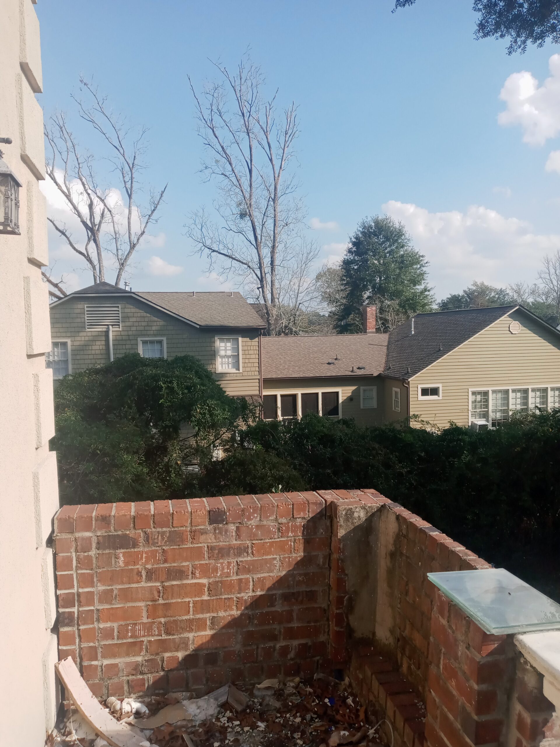 A view from a balcony showcasing several houses and trees against a clear blue sky.